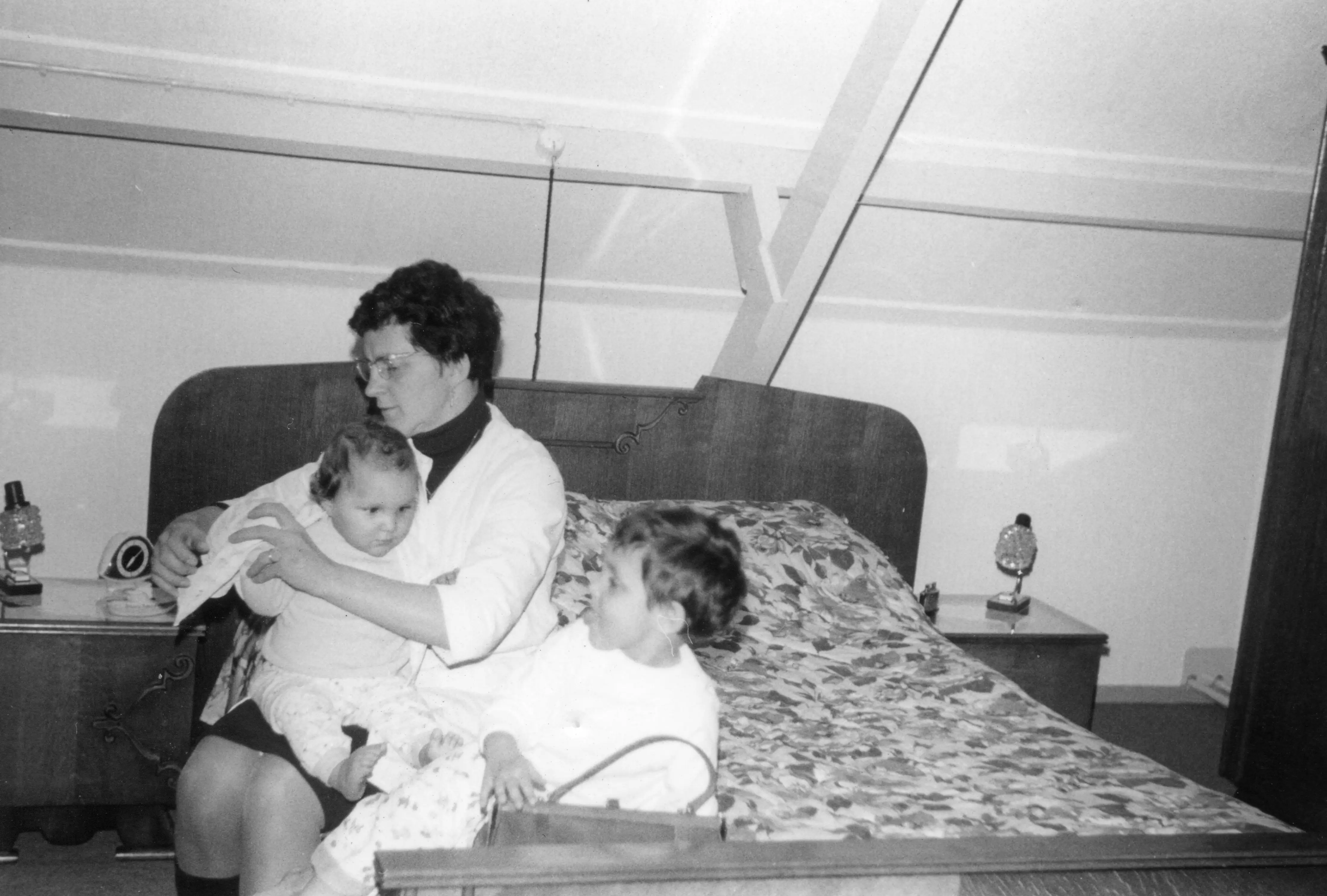 Pim Uijttewaal wordt door zijn moeder aangekleed; Karin kijkt toe en steekt haar tong uit, circa 1968.