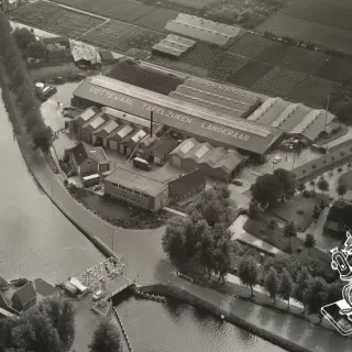 Luchtfoto van conservenfabriek L.P. Uijttewaal aan de Kattenbrug, Westkanaalweg 1. Aan de andere kant van het dak staat de tekst Jumping Fox Gherkins All Over The World. De gedach…